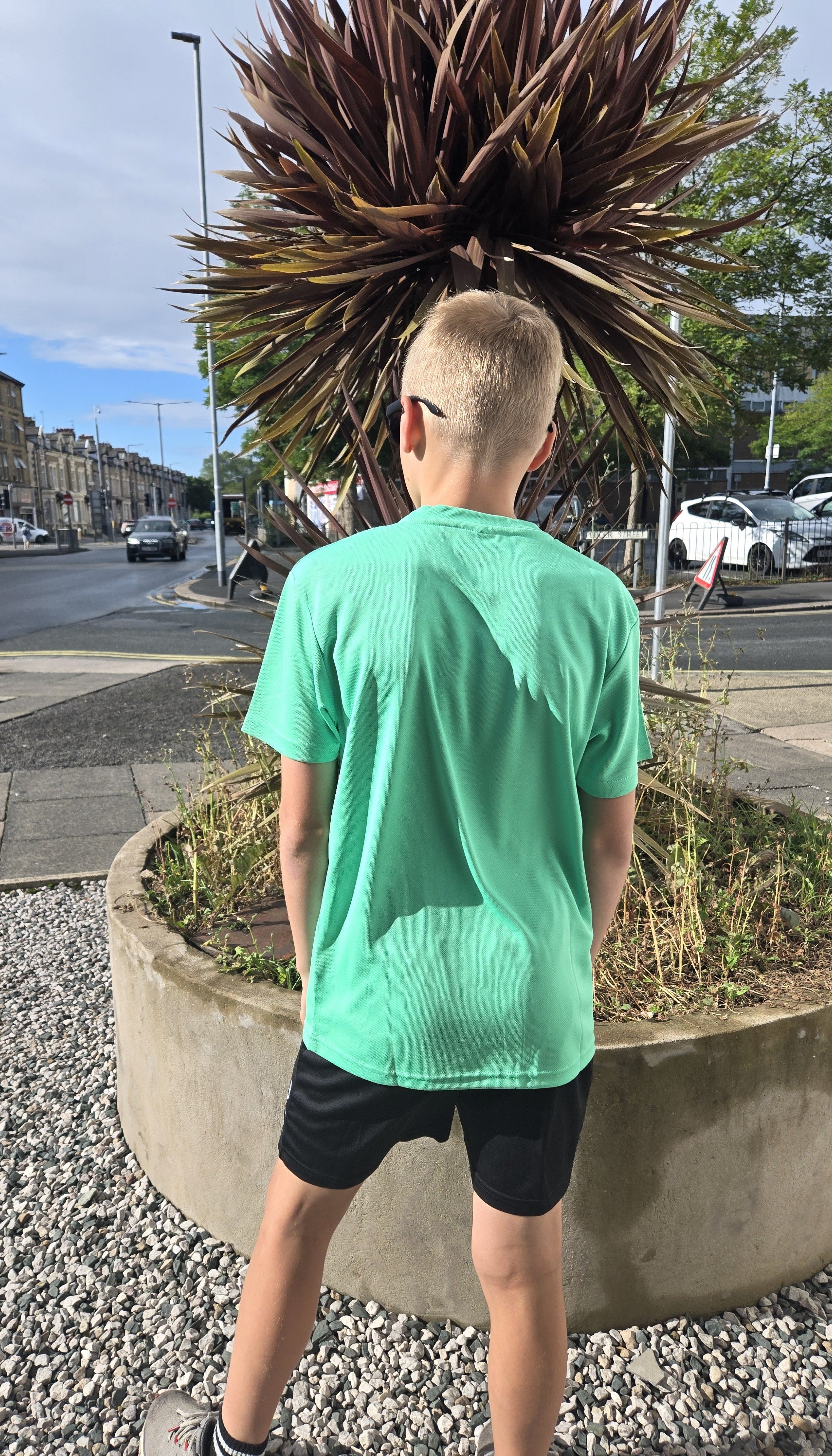 Teenager wearing black shorts with green sports tshirt