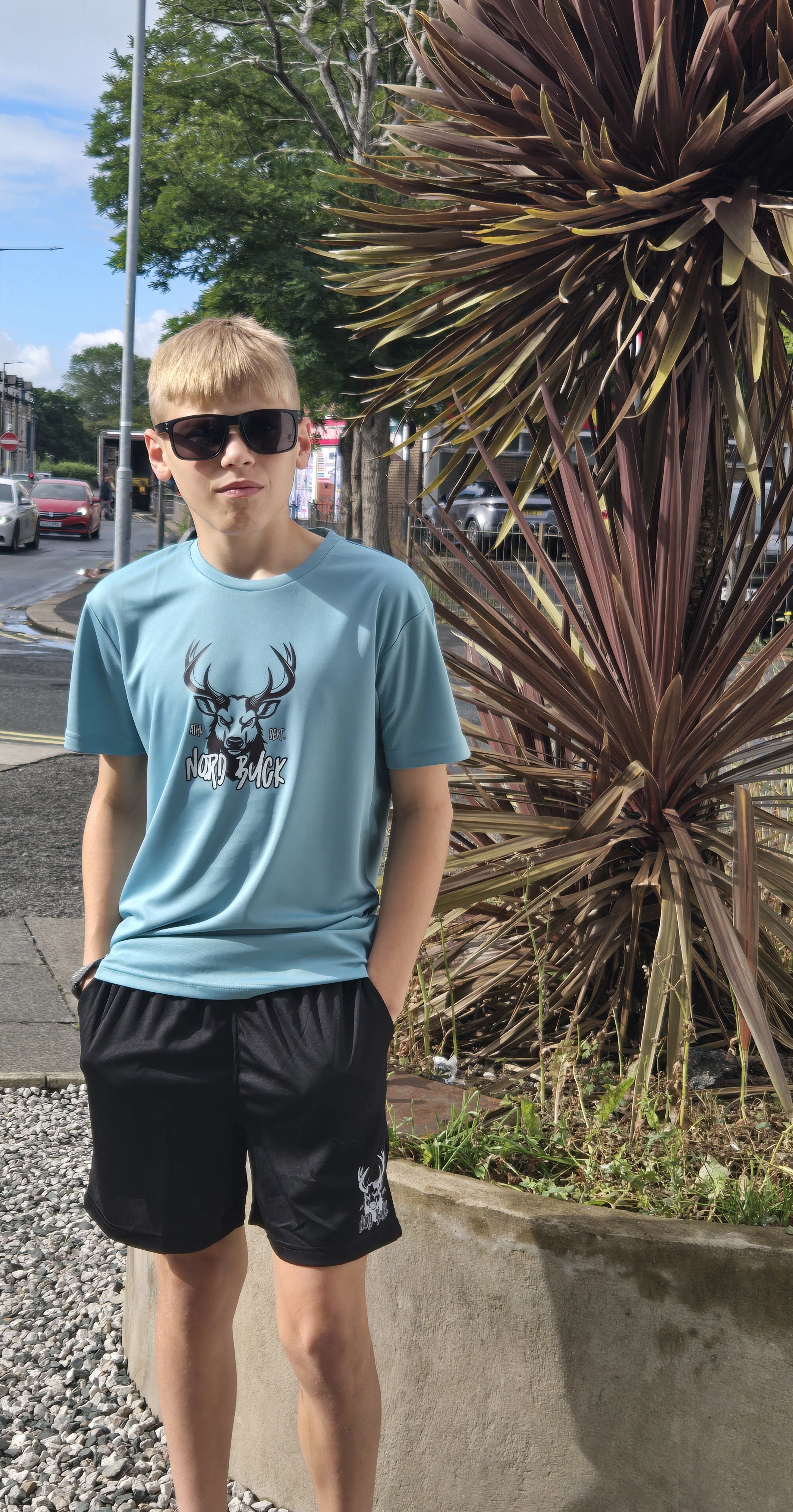 Teenage wearing light blue sports tshirt outside in the sun