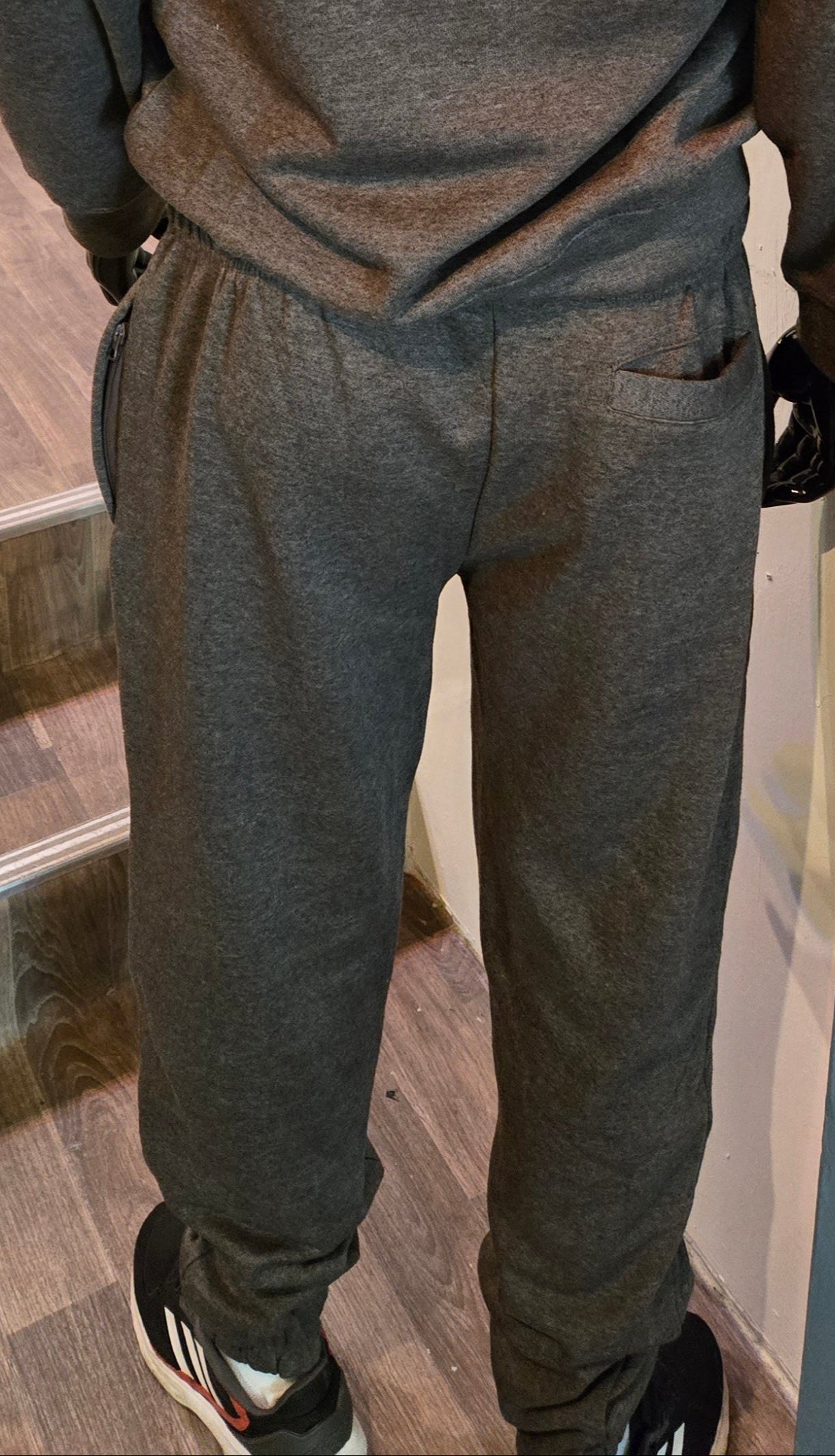 Person wearing a dark gray hoodie and pants in a store setting