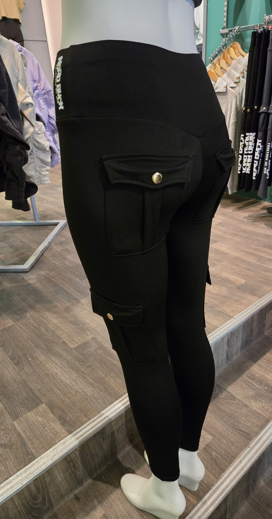 Person wearing black pants with a button in a store setting