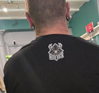Person wearing a black t-shirt with a logo on the back, standing indoors.
