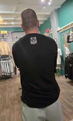 Person wearing a black t-shirt with a logo in a clothing store