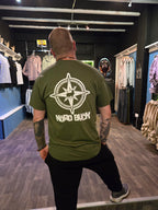 Person wearing a green t-shirt with a compass stag design in an indoor setting