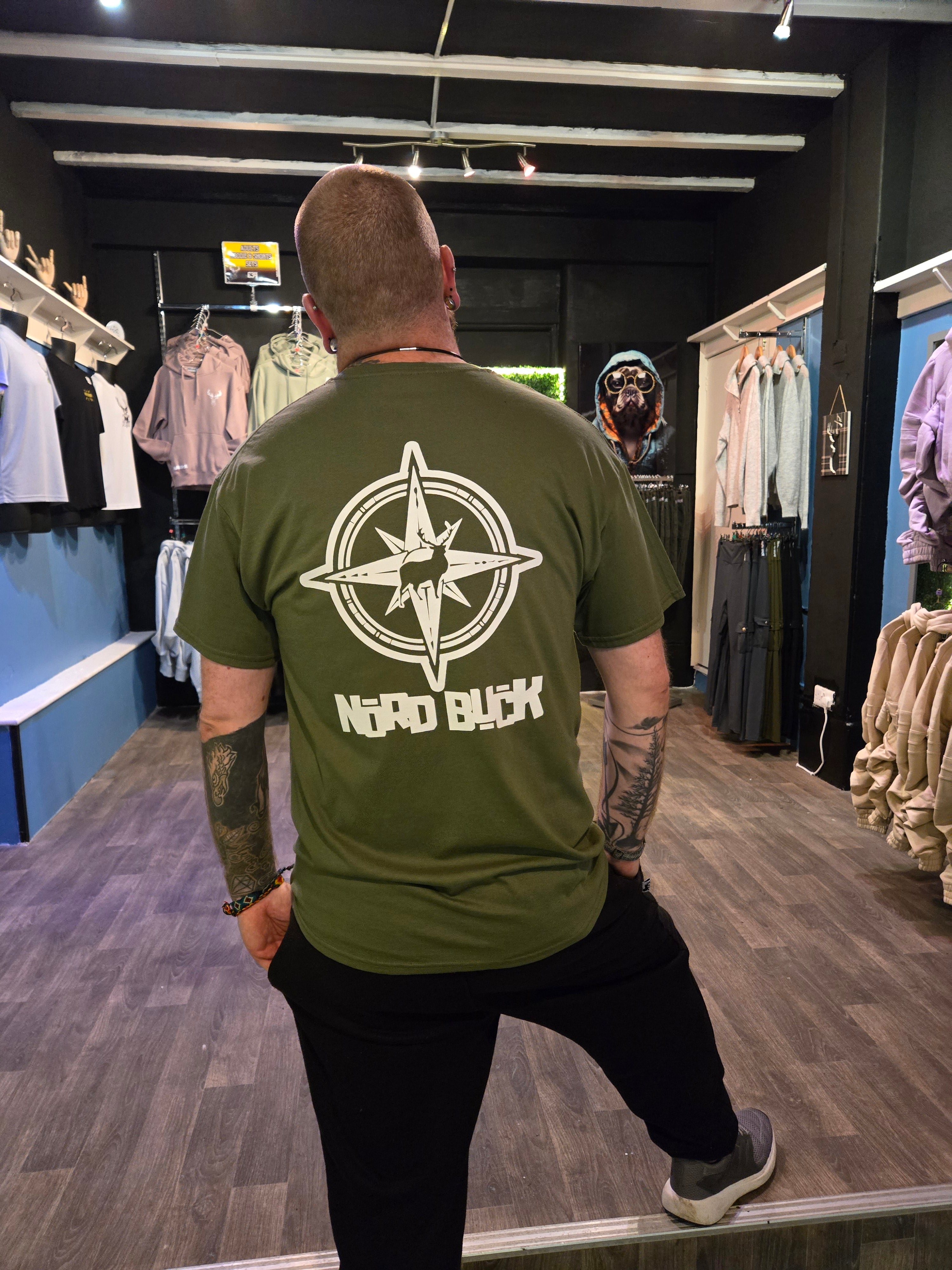 Person wearing a green t-shirt with a compass stag design in an indoor setting