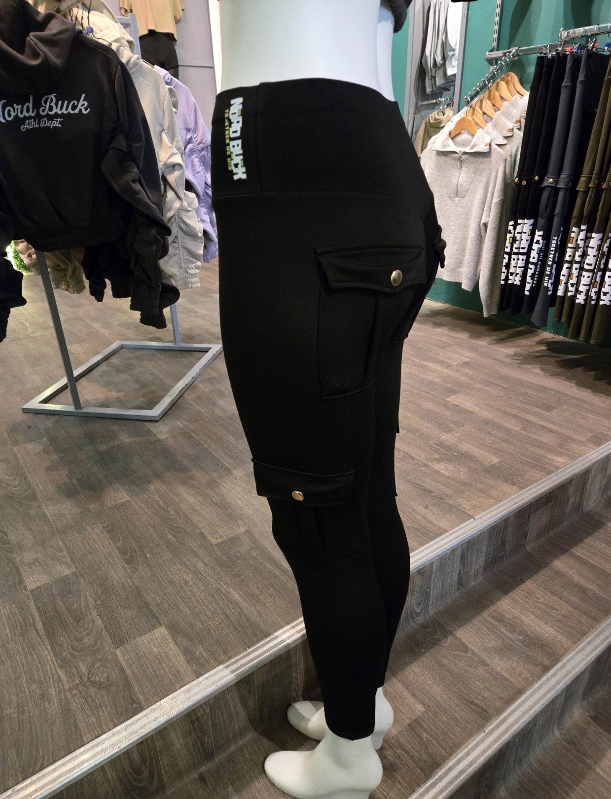 Person wearing black leggings pants with visible branding in a store setting