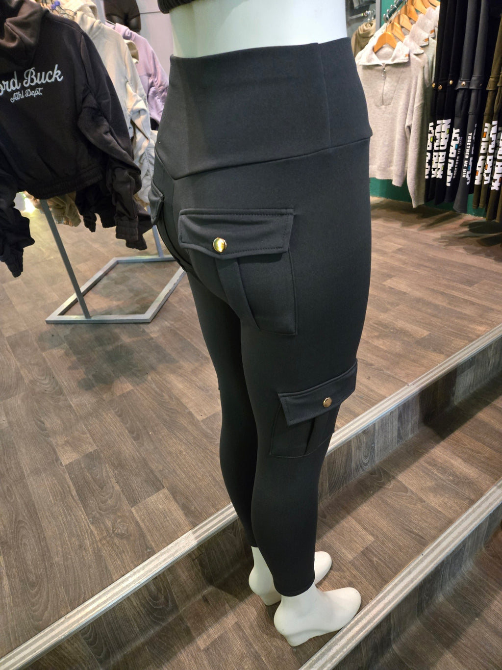 Person wearing grey pants with gold buttons in a store setting
