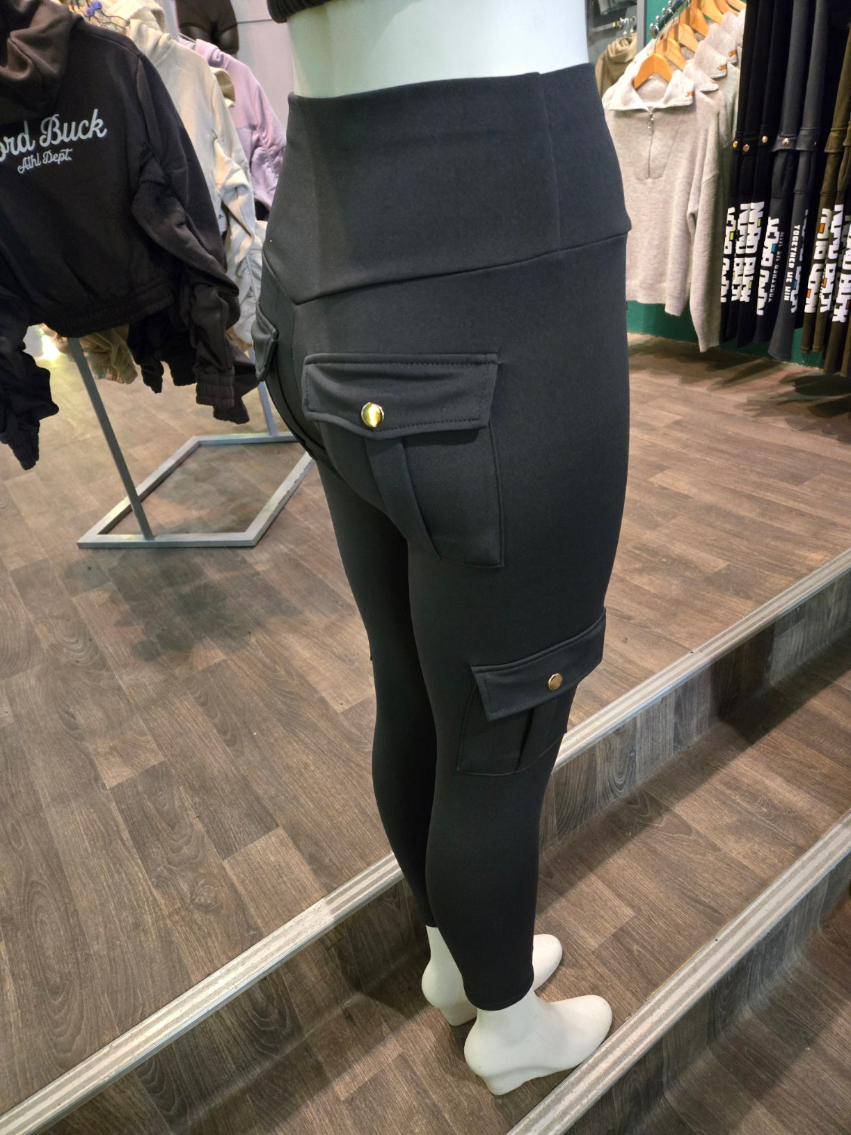 Person wearing grey pants with gold buttons in a store setting