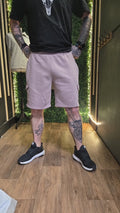 Person wearing a black t-shirt, light purple cargo shorts, and black sneakers with tattoos on arms and legs.
