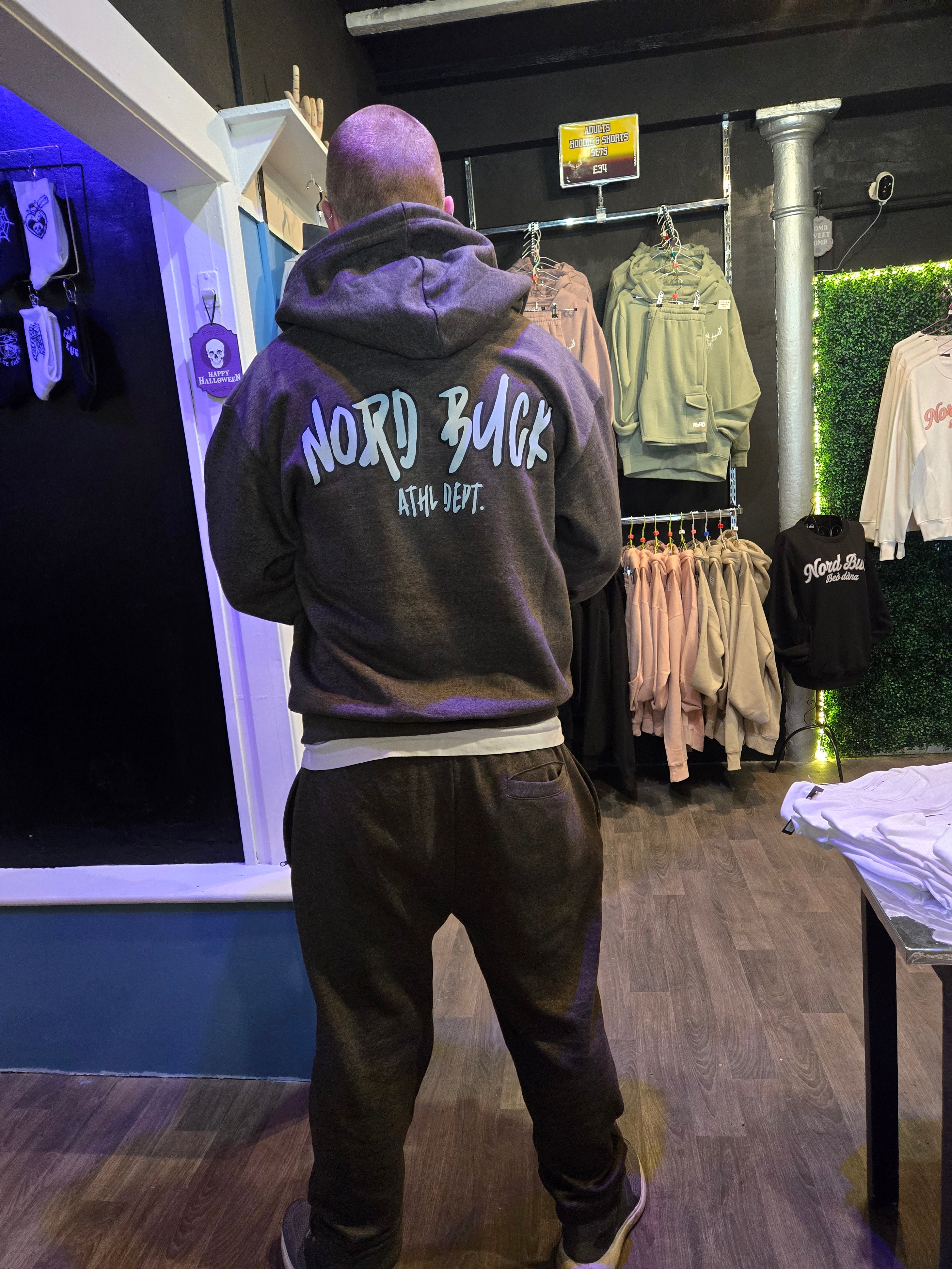 Person wearing a hoodie with text, standing in front of a display case with products.