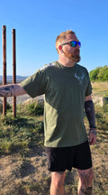 Man wearing green stag tshirt with nord buck logo on a beach