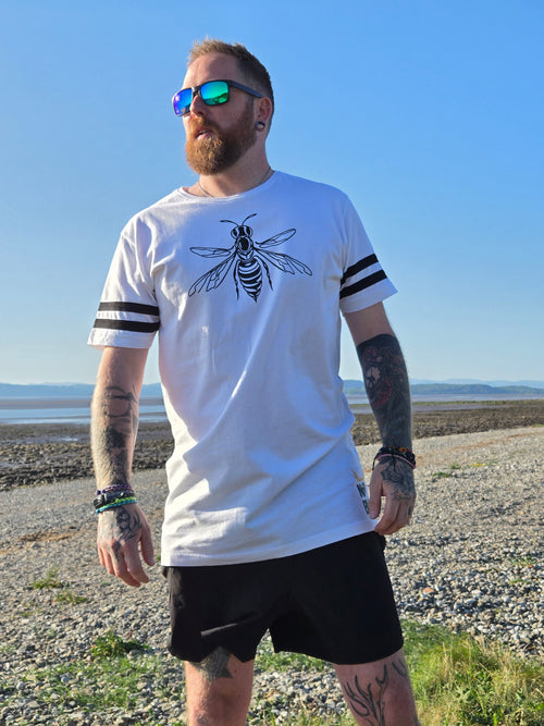 Man wearing a long white tshirt with a bee design on the front