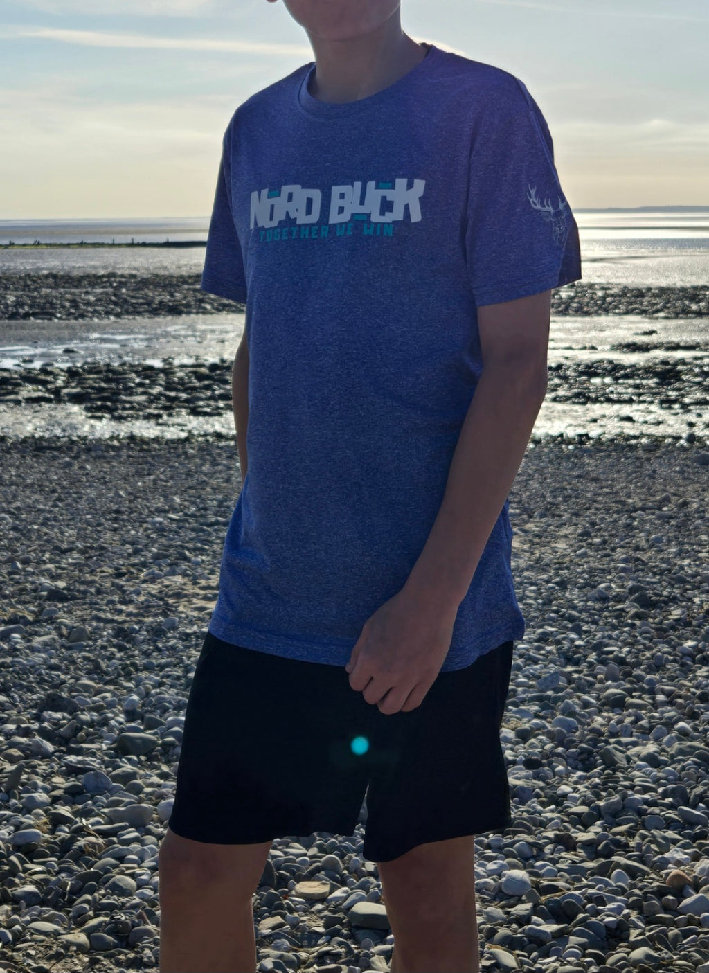 Teenager on the beach wearing a blue tshirt with Nord Buck across the chest 