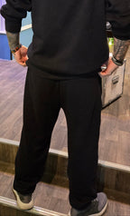 Person wearing a black hoodie and pants in a store setting