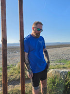 Man wearing blue stag tshirt with nord buck logo on a beach