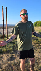 Man wearing green stag tshirt with nord buck logo on a beach