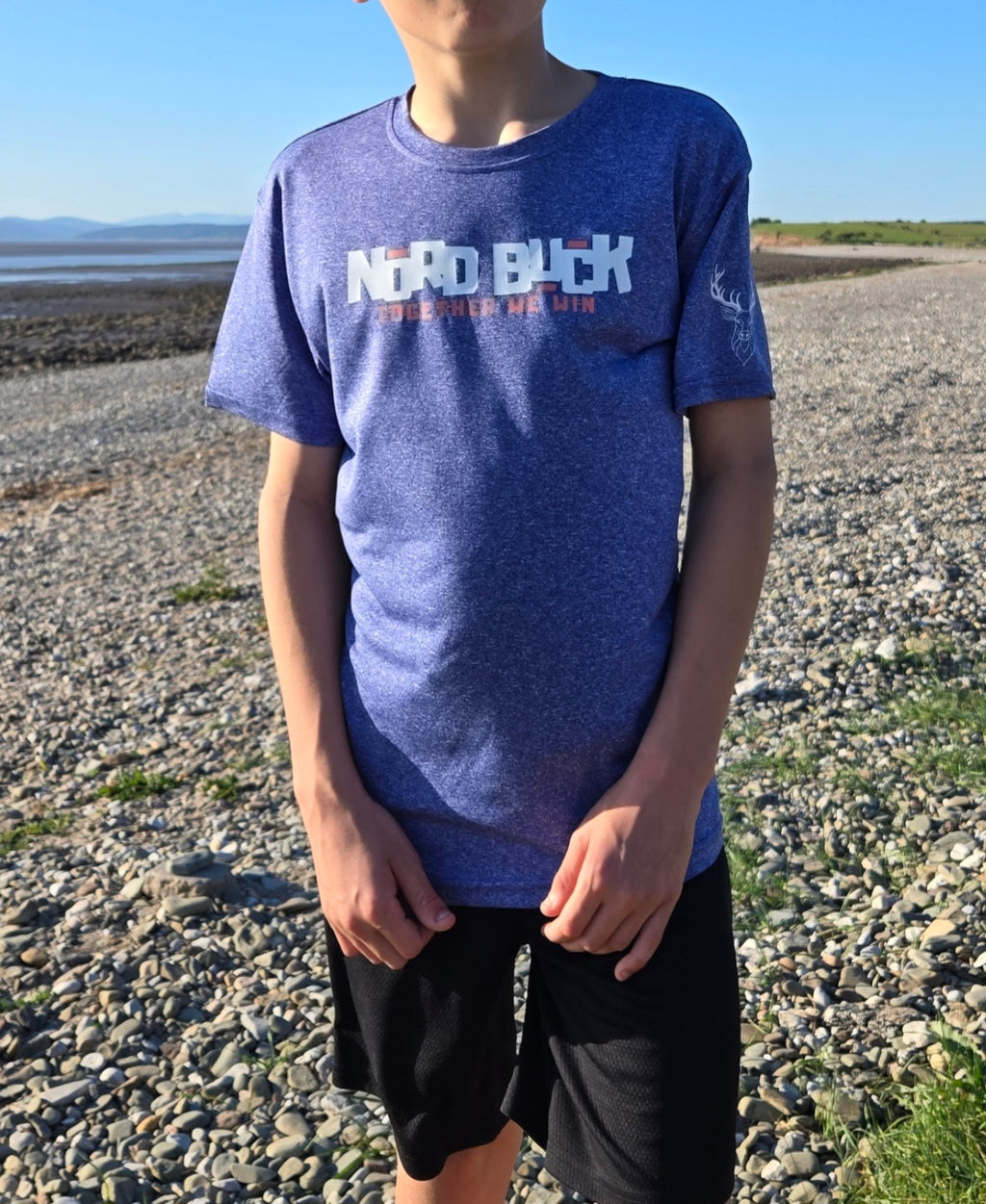 Teenager on the beach wearing a blue tshirt with Nord Buck across the chest 